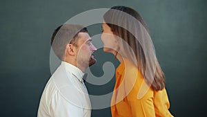 Portrait of couple kissing on gray background, girl leaving lipstick traces on guy