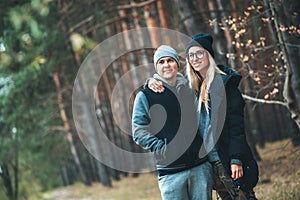 Portrait of couple in love standing in beautiful forest hugging and smiling. Family spending time in outdoor.