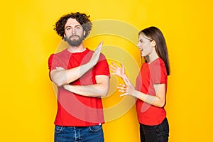 Portrait couple man and woman screaming at each other during fight over yellow background