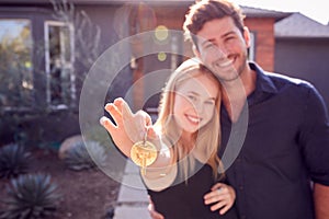 Portrait Of Couple With Pregnant Wife Standing Outdoors In Front Of New Home Holding Keys