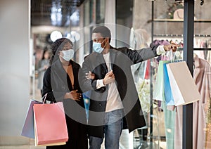 Portrait of couple in protective masks shopping in city mall during coronavirus pandemic and social distancing