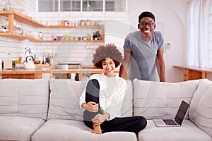 Portrait Of Couple Relaxing On Sofa At Home Looking At Laptop Together