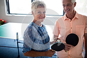 Portrait of a couple of seniors front of a ping pong table