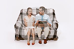 Portrait of couple sitting on sofa and listening to the radio. Woman singing and dancing