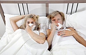 Portrait of couple suffering from cold lying on bed