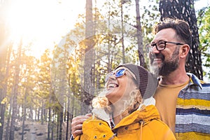 Portrait of couple of two happy people looking at the trees in the forest and enjoying together the nature outdoors