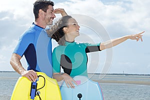 portrait couple wearing swimsuits with surfboard