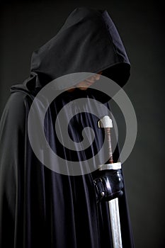 Portrait of a courageous warrior wanderer in a black cloak and sword in hand.