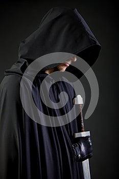 Portrait of a courageous warrior wanderer in a black cloak and sword in hand. photo
