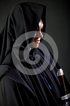 Portrait of a courageous warrior wanderer in a black cloak and sword in hand.