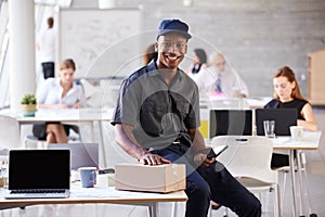 Portrait Of Courier Collecting Package From Busy Office