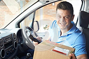 Portrait Of Courier In Van Delivering Package To House