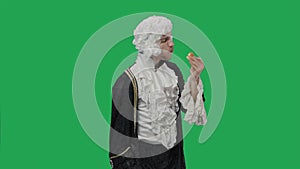 Portrait of courtier gentleman in black historical vintage suit and wig, greedily eating cheeseburger. Young man posing