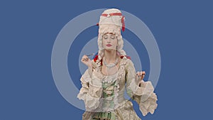 Portrait of courtier lady in white vintage lace dress and wig is doing makeup with a brush. Young woman posing in studio