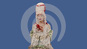 Portrait of courtier lady in white vintage lace dress and wig texting on her phone. Young woman posing in studio with