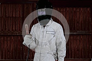 Portrait of craftsman welder in white uniform holding arc welding torch in hands. Industrial worker concept.