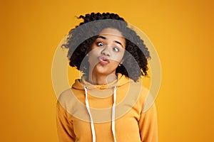 Portrait of crazy african american young woman with beautiful smile dressed in casual clothes over yellow background.
