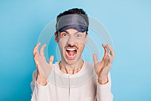 Portrait of crazy aggressive brunet guy wearing eye mask shouting bad mood isolated over bright blue color background