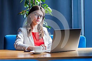 Portrait of crazy beautiful stylish brunette young woman in glasses sitting and looking at laptop display with crossed eyes funny