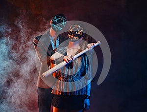 Portrait of crazy couple in masks with bat