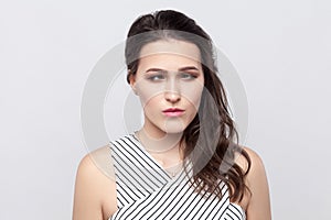 Portrait of crazy funny beautiful young brunette woman with makeup and striped dress standing and looking at camera with crossed