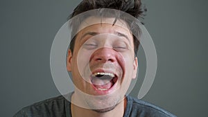 Portrait of crazy laughter of a drunk or drugged young man looking at camera.