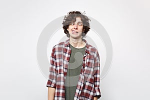 Portrait of crazy loony young man in casual clothes with beveled eyes and showing tongue isolated on white wall