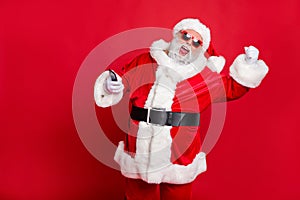 Portrait of crazy santa claus in hat using cell phone device raising fists screaming yes having newyear party wearing