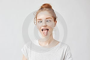 Portrait of crazy and silly yet beautiful freckled girl with eyes crossed, puting out toungue fooling around. Pretending