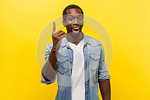 Portrait of creative inspired man pointing finger up, showing great idea sign. studio shot isolated on yellow background