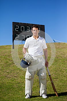 Portrait of cricket player standing against scoreboard