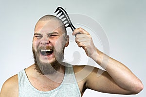 Portrait of cry bearded bald man holding a brush in his hand. The concept of hair loss and hair transplantation