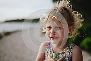 Portrait of crying blonde girl in summer outfit on walk during summer vacation, concept of beach holiday.