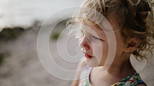 Portrait of crying blonde girl in summer outfit on walk during summer vacation, concept of beach holiday.