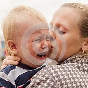 Portrait of a crying little boy who is being held