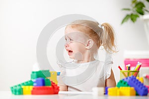 Portrait of crying little girl playing at table.Frustrated girl showing moody behavior and long face.
