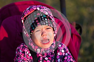 Portrait of crying little girl in pram outdoors
