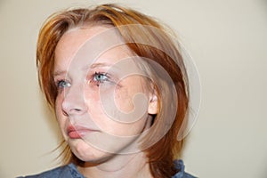 Portrait of a crying red-haired teenage girl with mascara smeared on her eyes