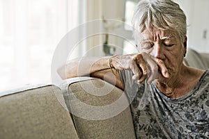 Portrait Of crying Senior Woman On Sofa Suffering From Depression