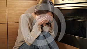Portrait of crying teenage girl hiding her face in hands. Mental problems and depression of teens