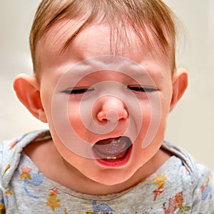 Portrait of a crying toddler baby boy. The face of an unhappy child with tears in his eyes, close-up