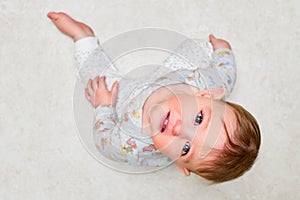 Portrait of a crying toddler boy sitting on the floor. Face of an unhappy child with tears in his eyes, close-up