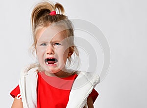 Portrait of crying, yelling, abused baby girl in red t-shirt. Got lost. Helpless. Family conflict, violence