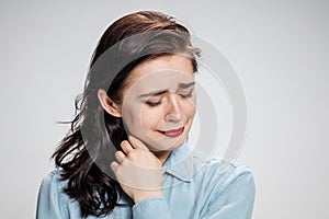The portrait of a crying young lonely woman on gray