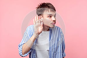 Portrait of curious attentive brown-haired man with small beard and mustache listening to rumor. isolated on pink background