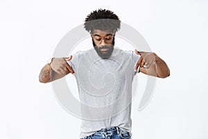 Portrait of curious handsome masucline african american male with beard and curly hair in glasses with tattoos looking