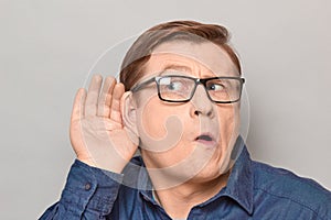 Portrait of curious man placing hand near ear and eavesdropping