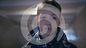 Portrait of a Curious and Trusting Boy Looking Intently at the Camera in an Underground Passage, Followed by Putting on