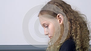 Portrait curly girl looking down profile view on gray background. Side view teenager girl reading or looking something