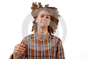 Portrait of a curly-haired young man with a wooden comb in full hair smiling on a white isolated background. male hair care